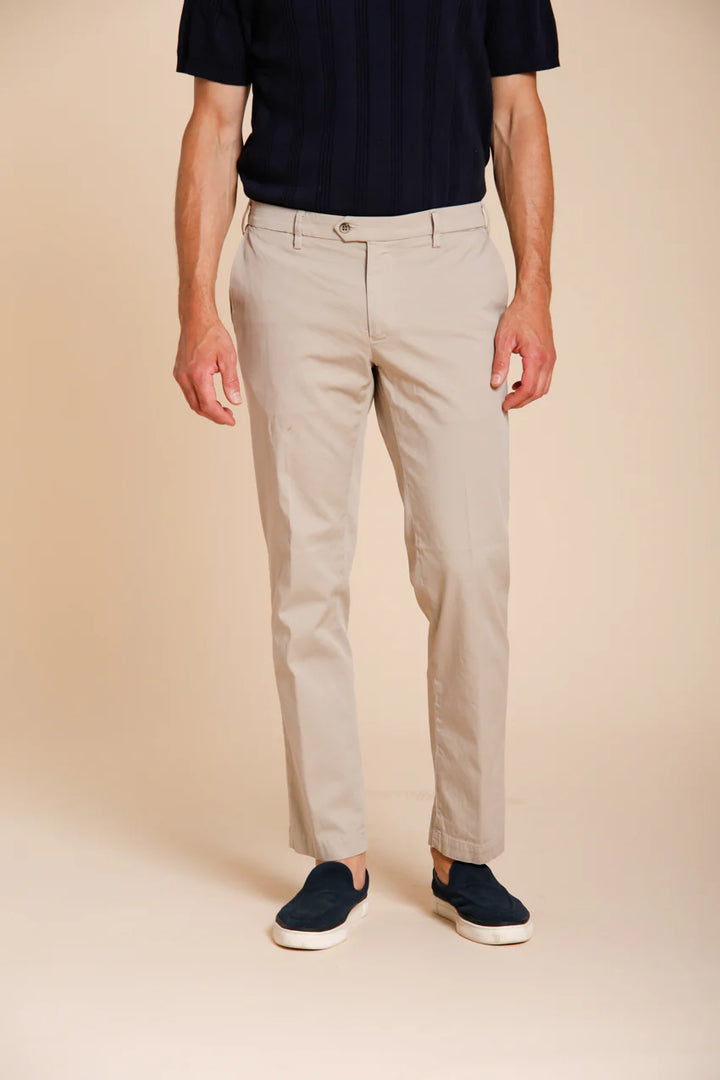 Person wearing beige pants and black shoes on a beige background