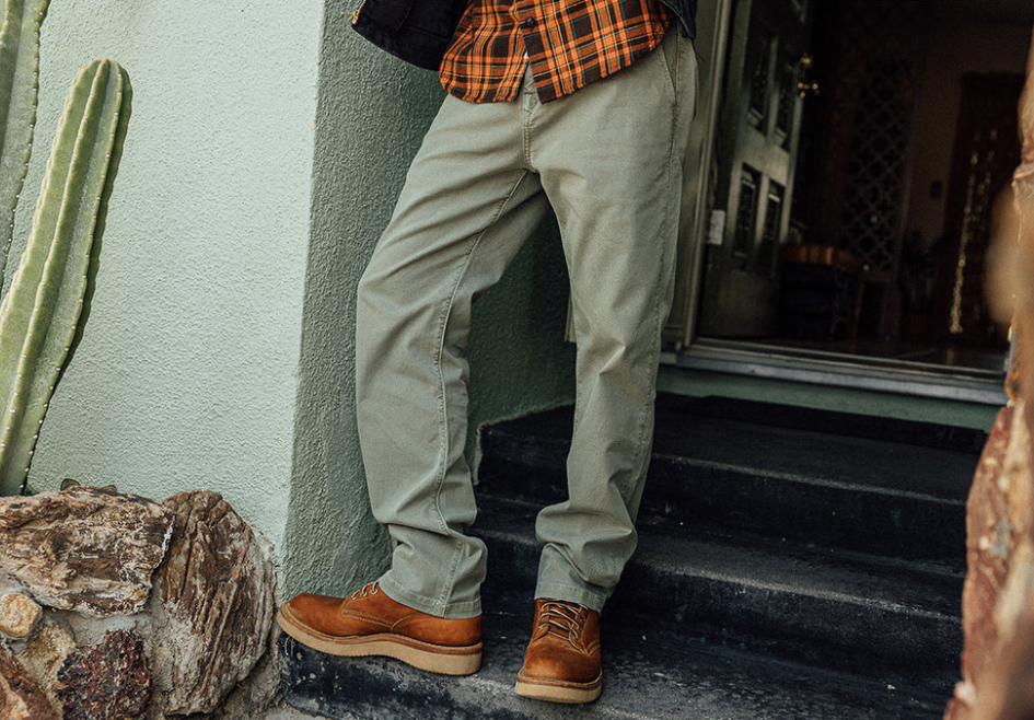 Person wearing beige pants and brown shoes standing on steps next to a cactus plant.