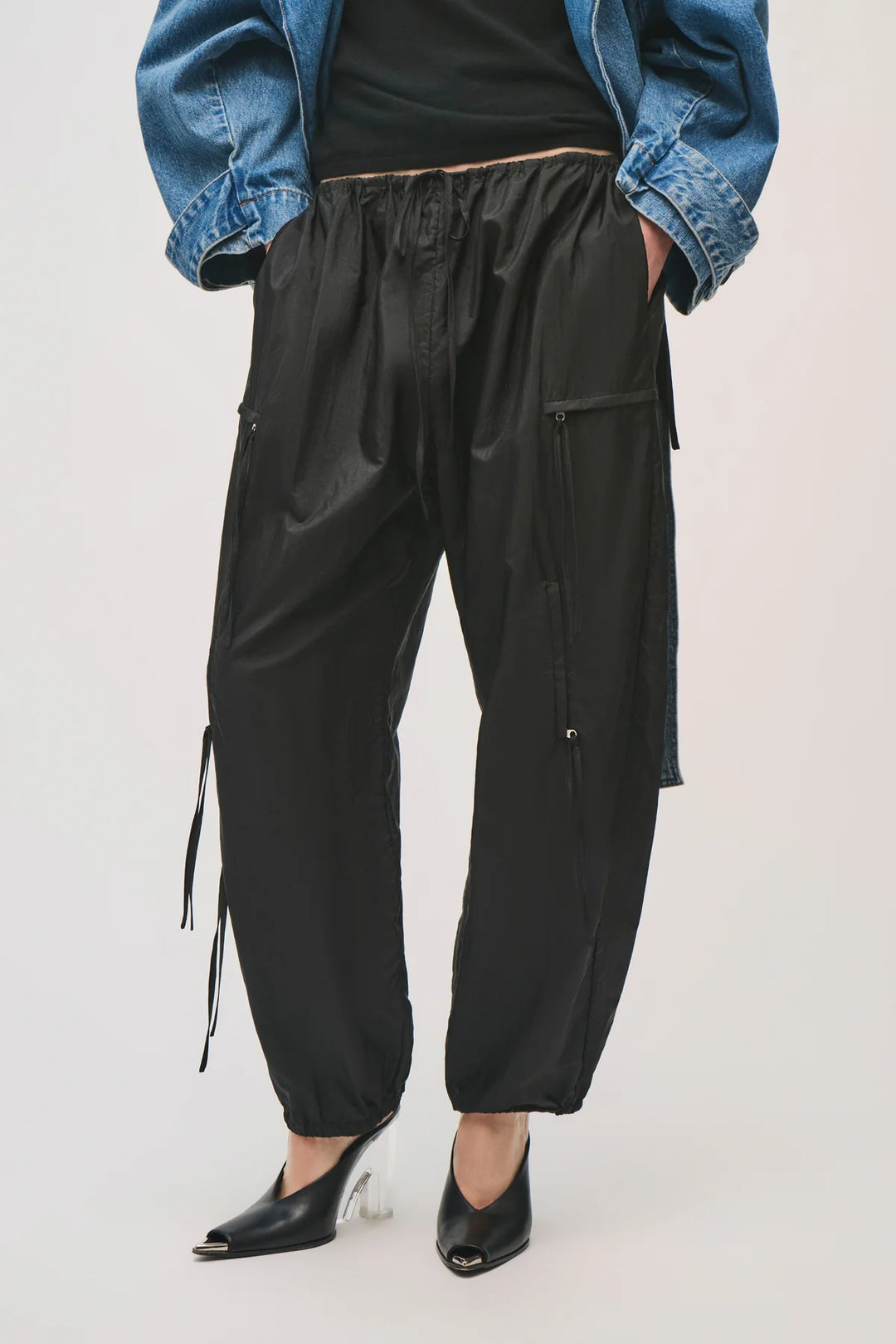Person wearing black cargo pants with a blue denim jacket on a white background