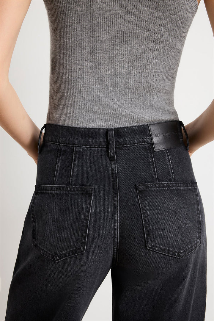 Person wearing black high-waisted jeans and a gray ribbed top on a light gray background