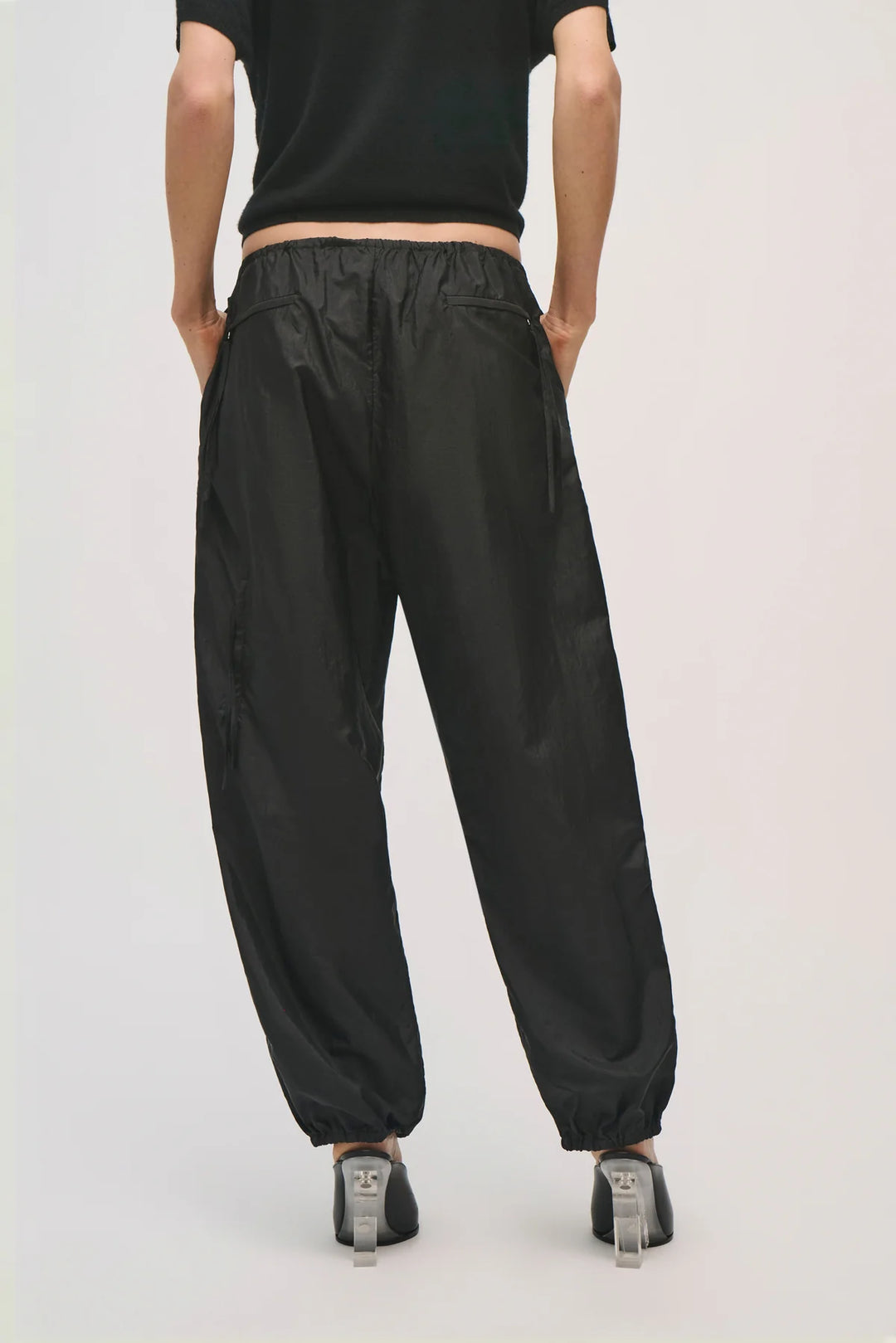 Person wearing black high-waisted pants on a plain background