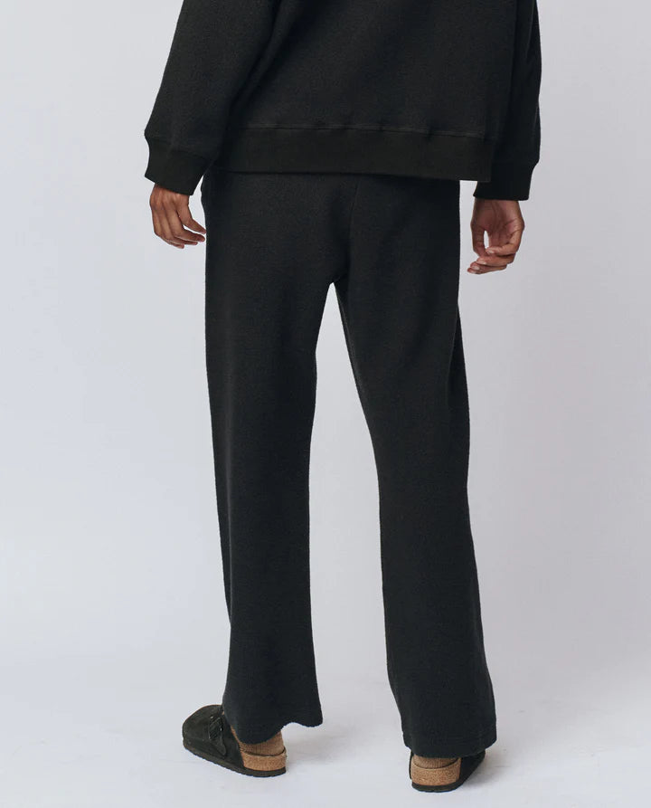 Person wearing black pants and a black top on a white background