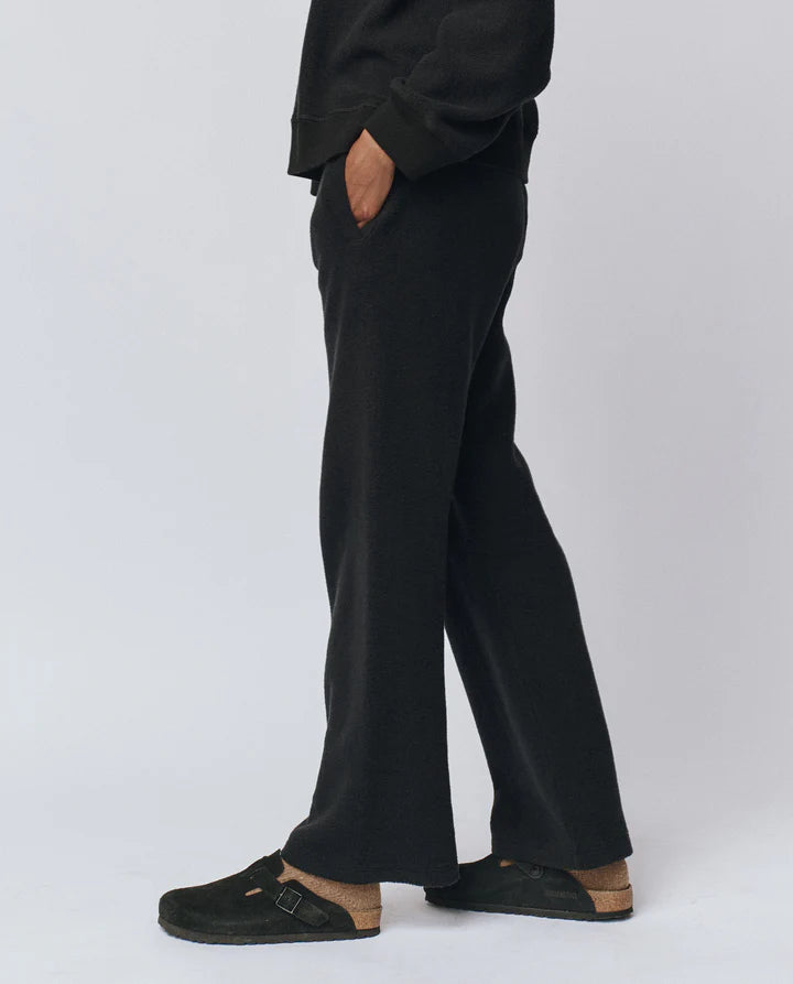 Person wearing black pants and black shoes on a white background