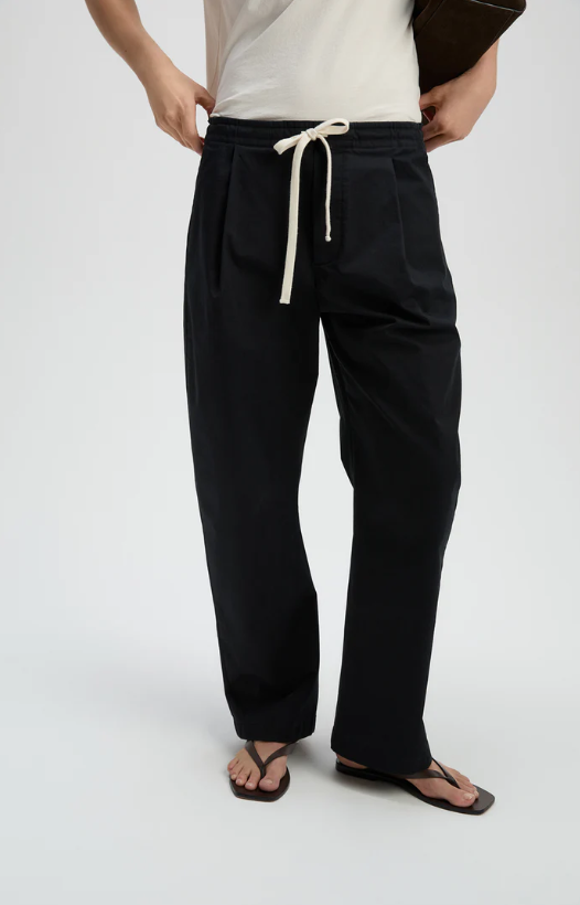 Person wearing black pants with a white drawstring on a light gray background