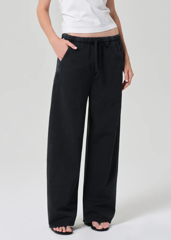 Person wearing black wide-leg pants and a white top on a light gray background