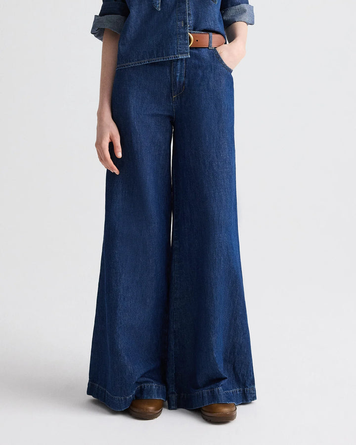 Person wearing blue denim wide-leg pants on a white background