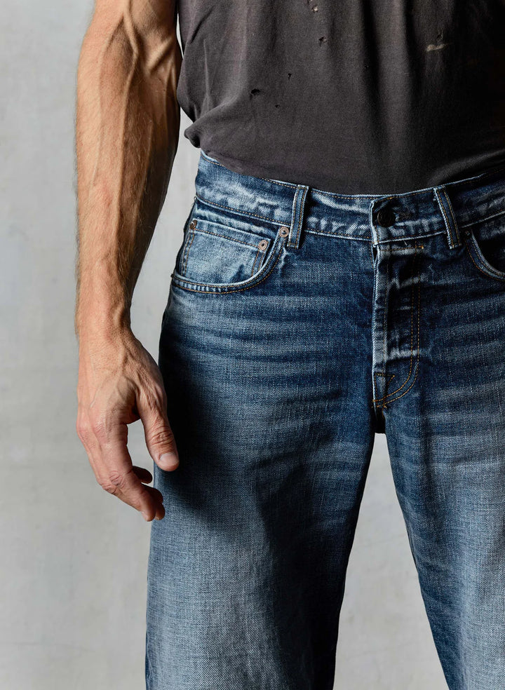 Person wearing blue jeans and a dark shirt against a neutral background