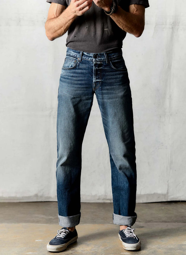 Person wearing blue jeans and a dark shirt against a plain background