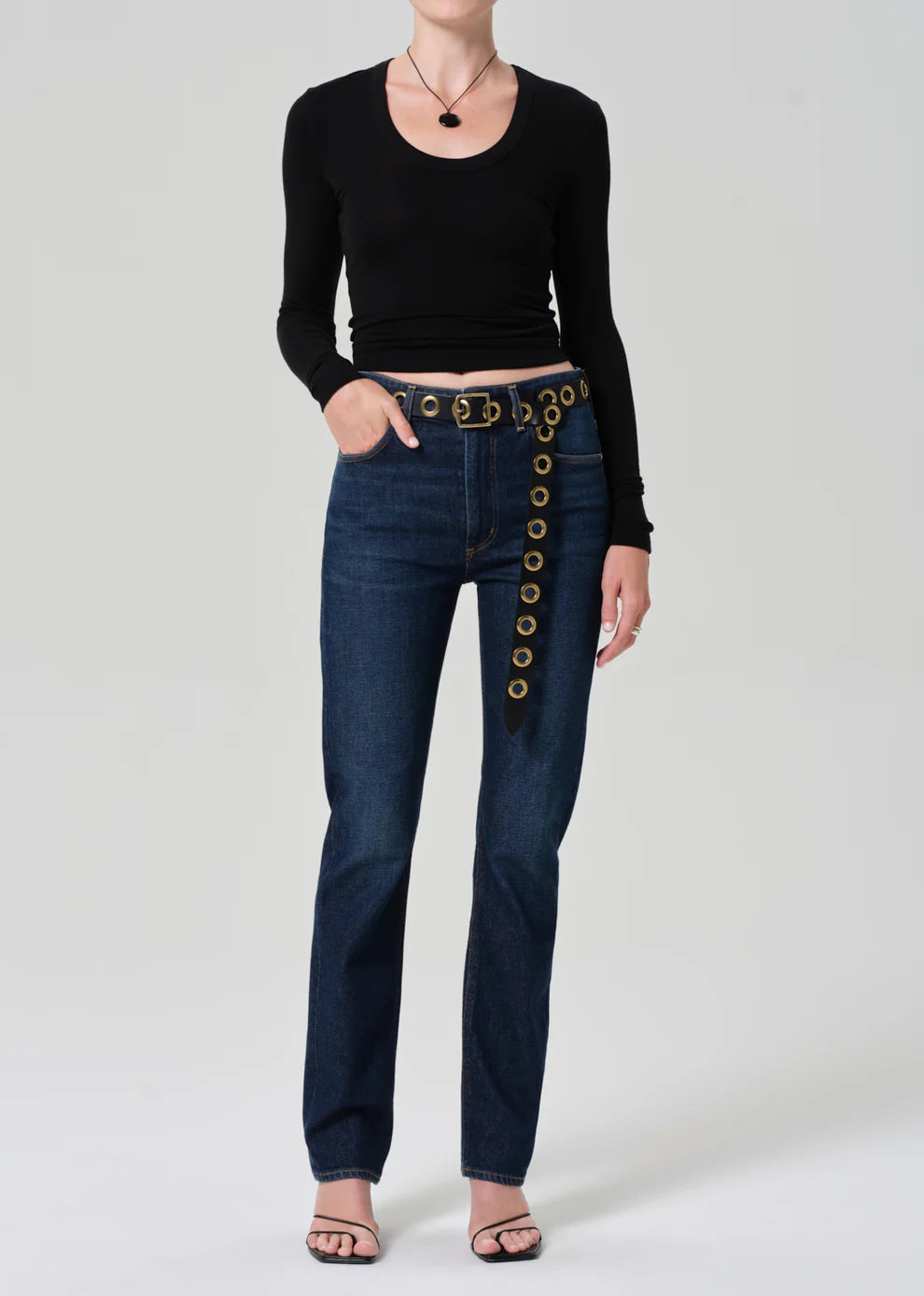 Person wearing blue jeans with decorative buttons on a white background