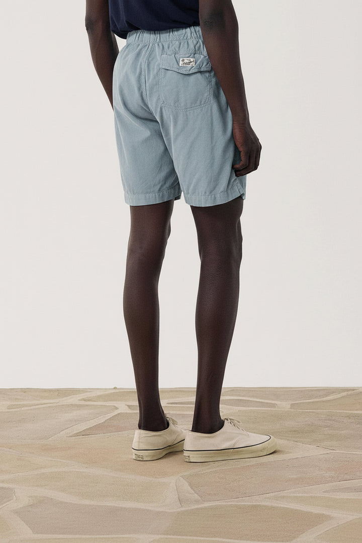 Person wearing blue shorts on a plain background