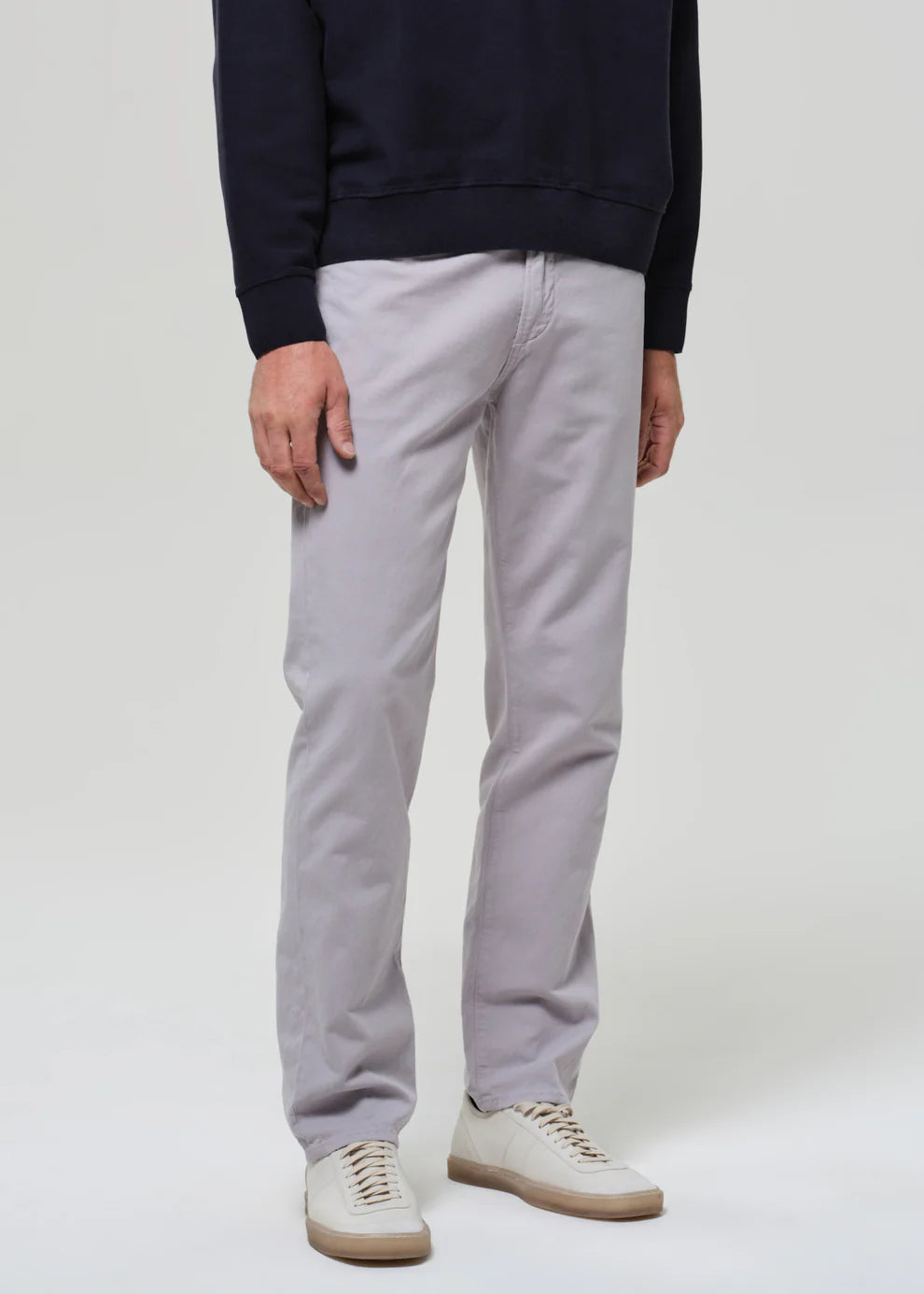 Person wearing light gray pants and a navy sweater on a white background