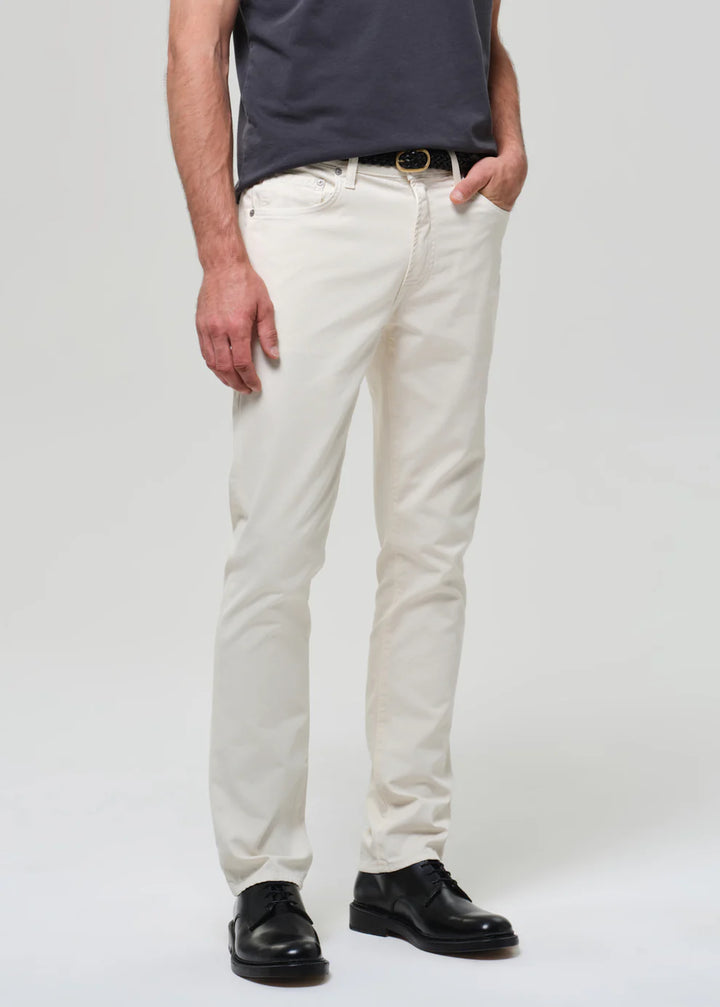 Person wearing white pants and black shoes on a plain background