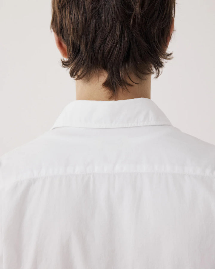 Person wearing a white shirt with a neutral background