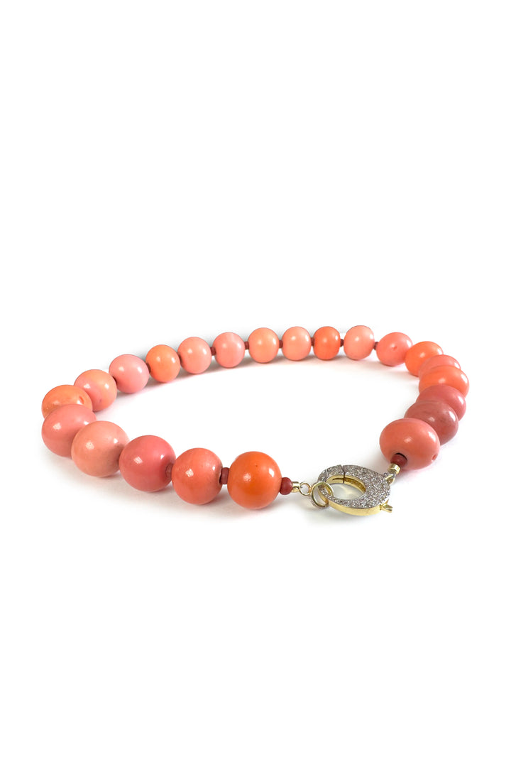 Pink beaded bracelet with a gold clasp on a white background