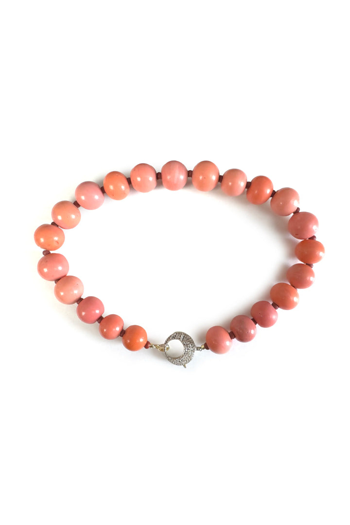 Pink beaded bracelet with a silver clasp on a white background