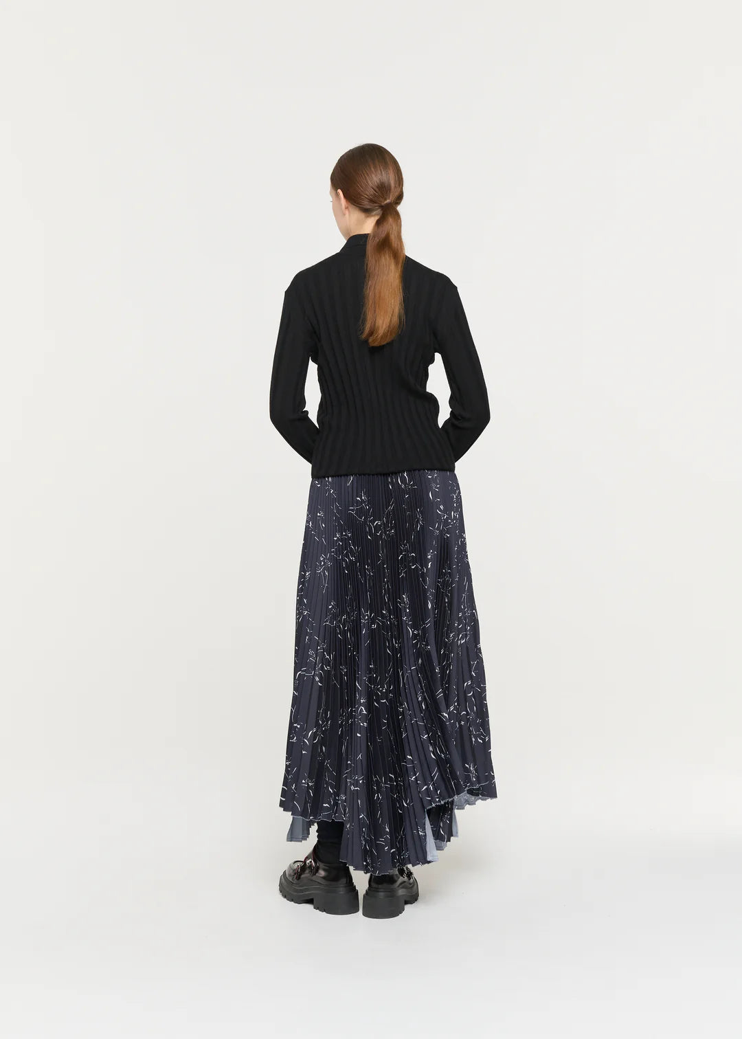 Person wearing a black top and dark blue skirt with star pattern on a white background