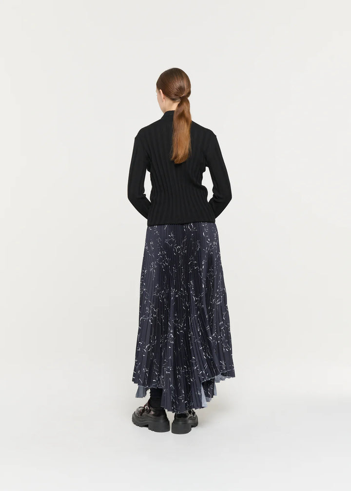 Person wearing a black top and dark blue skirt with star pattern on a white background
