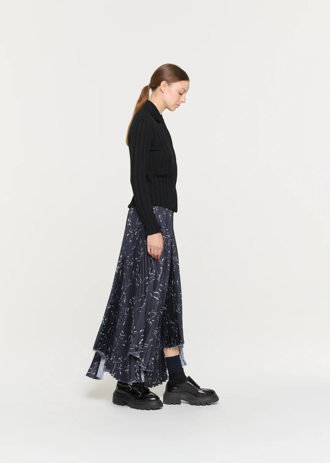 Woman wearing a black sweater and patterned skirt on a white background