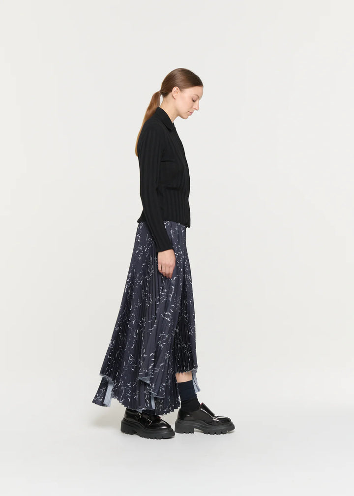 Woman wearing a black sweater and patterned skirt on a white background