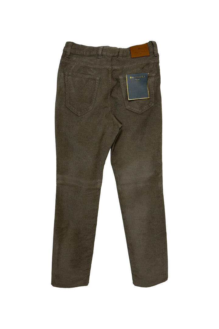Back view of a pair of dark brown corduroy jeans with a brown leather patch on the back waistband and a blue brand tag on the right pocket, set against a plain white background.