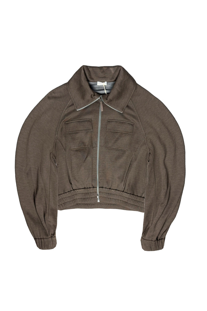 A cropped, long-sleeve zip-up jacket in a muted taupe-brown color, featuring a pointed collar, front zipper, and two flap chest pockets, shown flat against a plain white background.