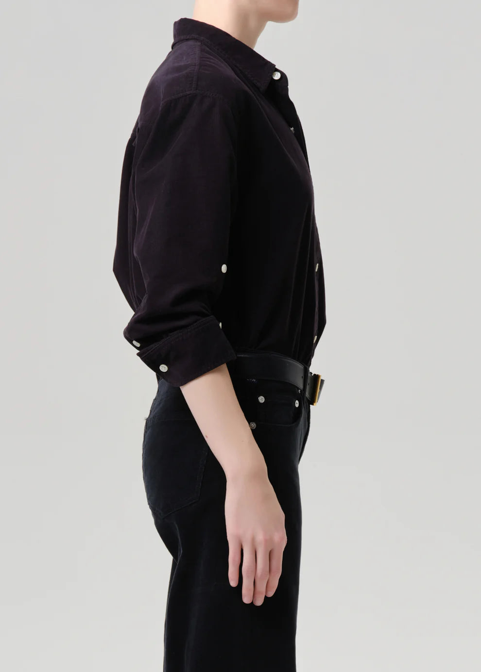 Person wearing a black shirt with rolled-up sleeves on a gray background