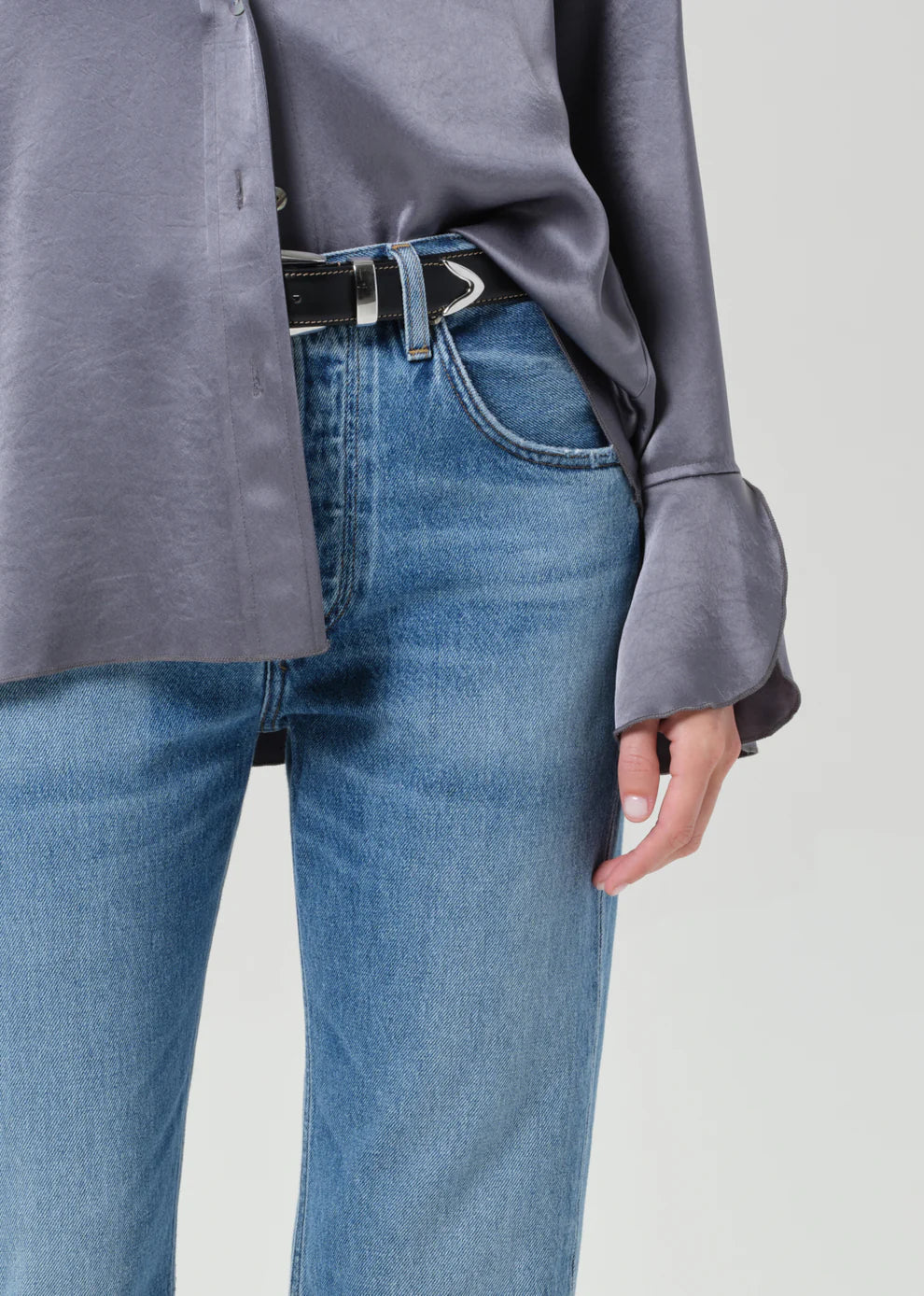 Person wearing a gray shirt and blue jeans on a light gray background