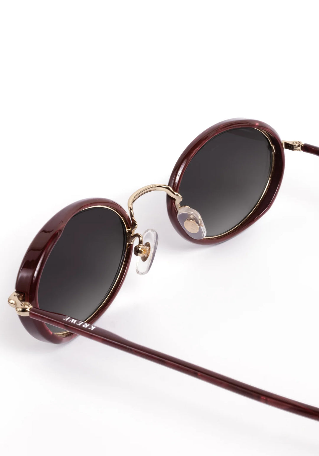 Oval sunglasses with dark brown acetate frames, gold metal rims, and dark lenses, shown on a clean white background.