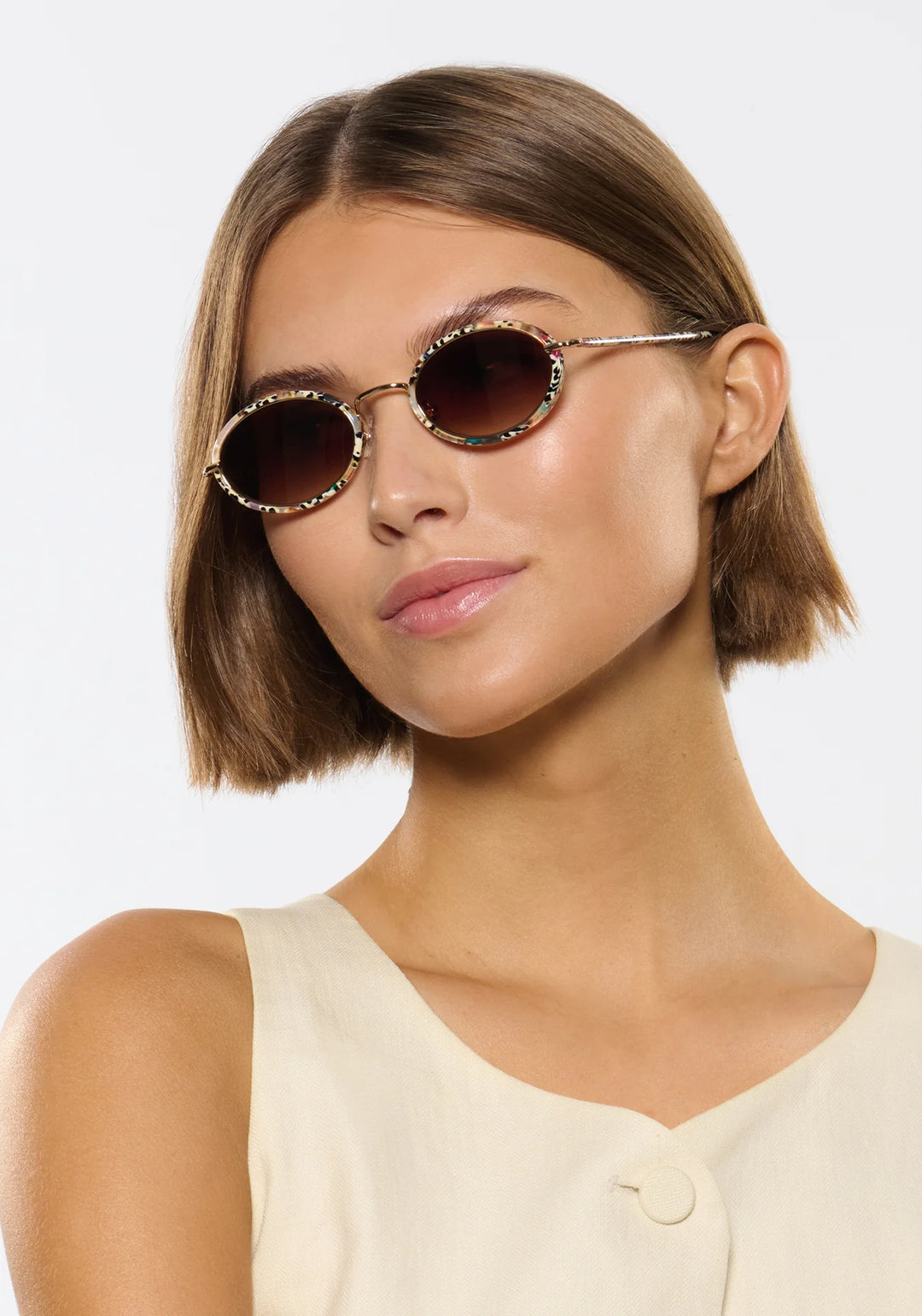 Woman wearing round sunglasses with a plain background