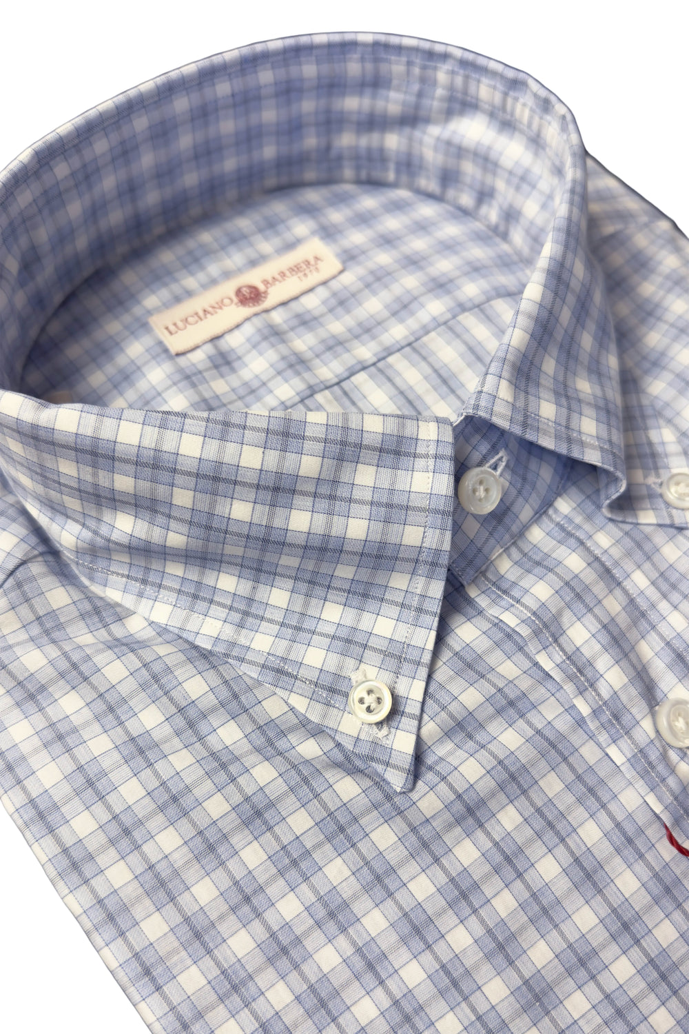 Close-up of a collared button-down shirt with a light blue and white gingham pattern, featuring a visible neck label that reads 'LUXE CHANTILLLES'.