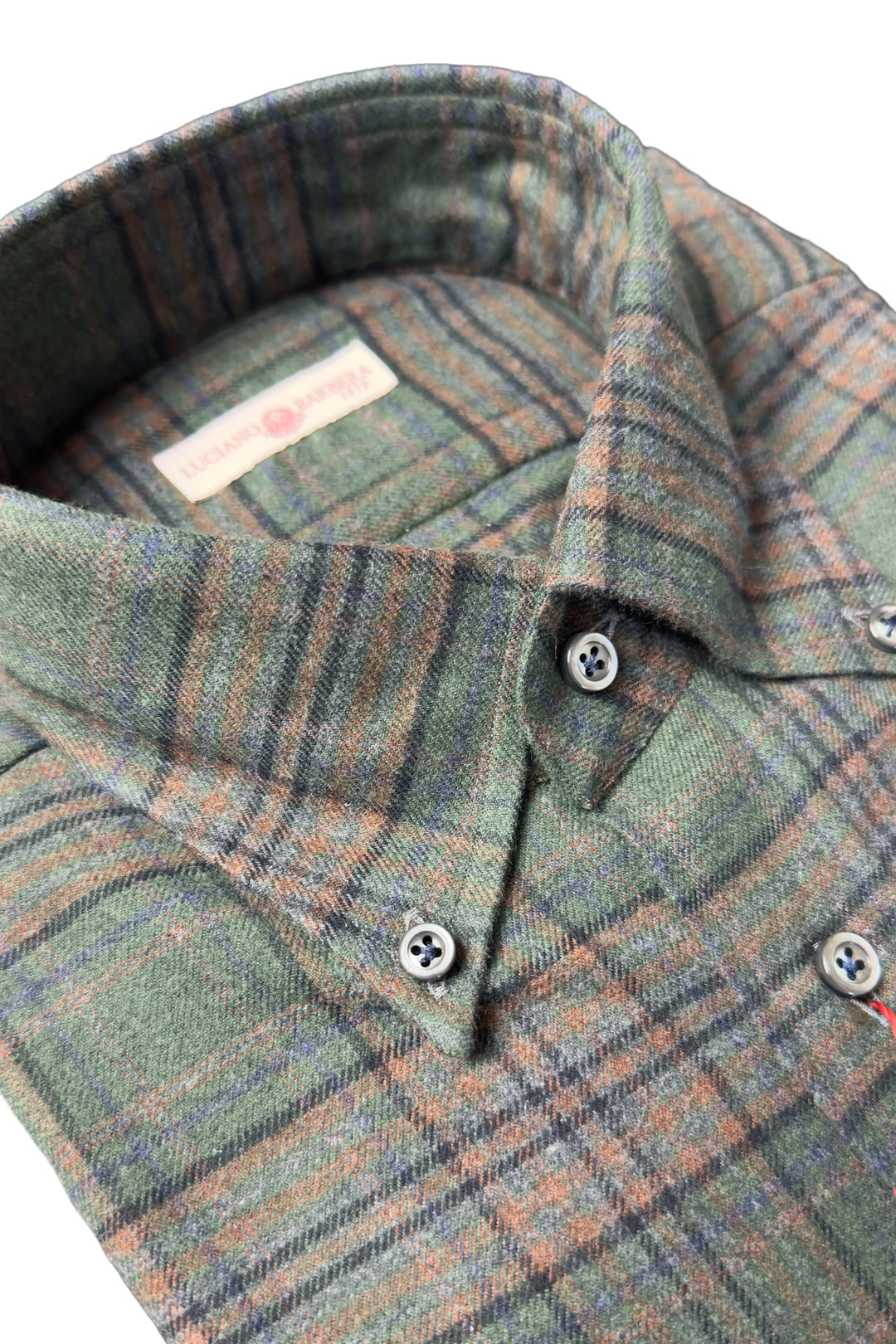 A close-up of a plaid button-down shirt collar in muted green, brown, and beige tones, with visible buttons and a small neck label.