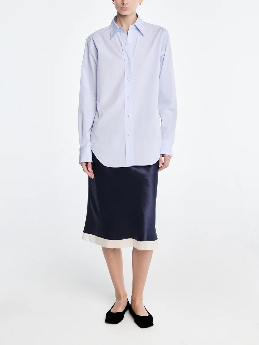 Person wearing a light blue striped shirt and navy satin skirt on a white background