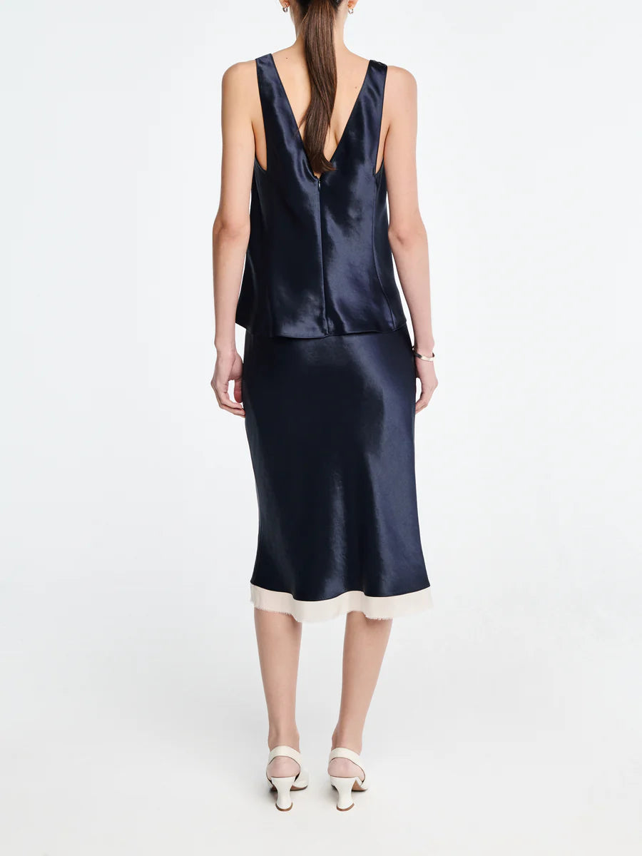 Woman wearing a navy satin dress with a plain white background