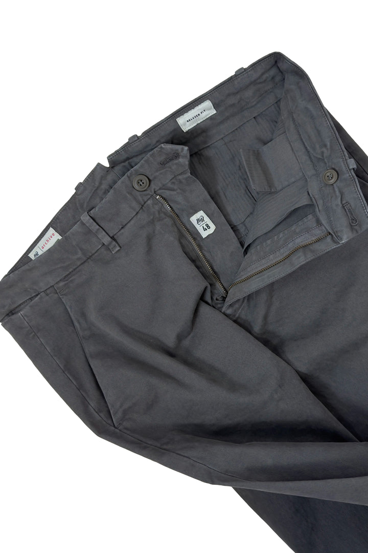Close-up of dark gray utility pants showing the inner waistband, button closure, belt loops, and interior pocket details against a white background.