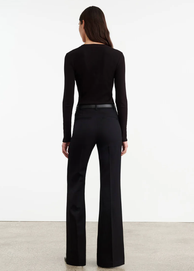 Person wearing a black long-sleeve top and black pants on a white background
