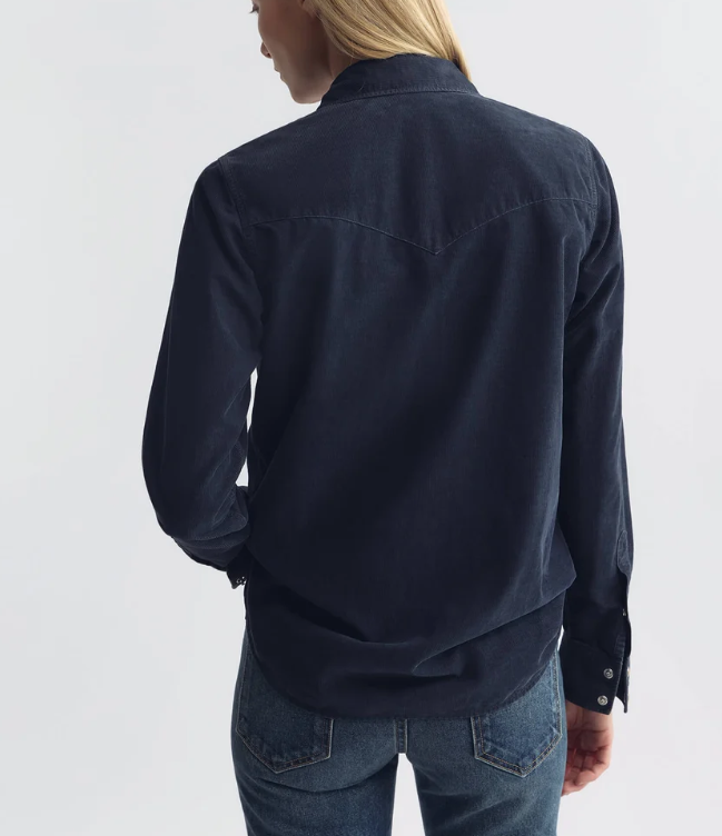 A woman shown from the back wearing a dark navy long-sleeve button-up shirt and blue jeans against a plain light gray studio background.