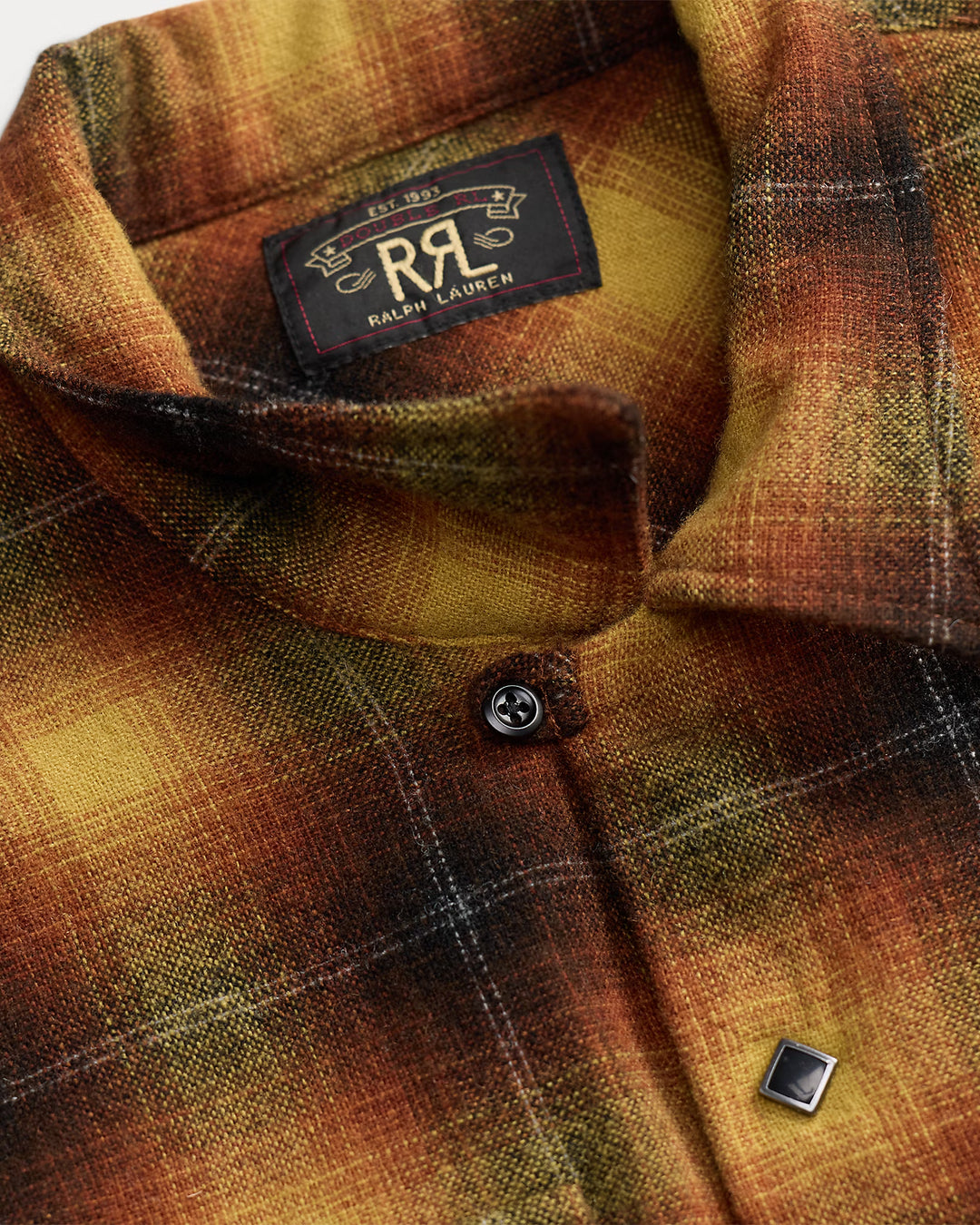Close-up of a Ralph Lauren plaid button-up shirt in warm autumn tones of brown, orange, and yellow, showing the inner neck label and a silver-toned chest button.