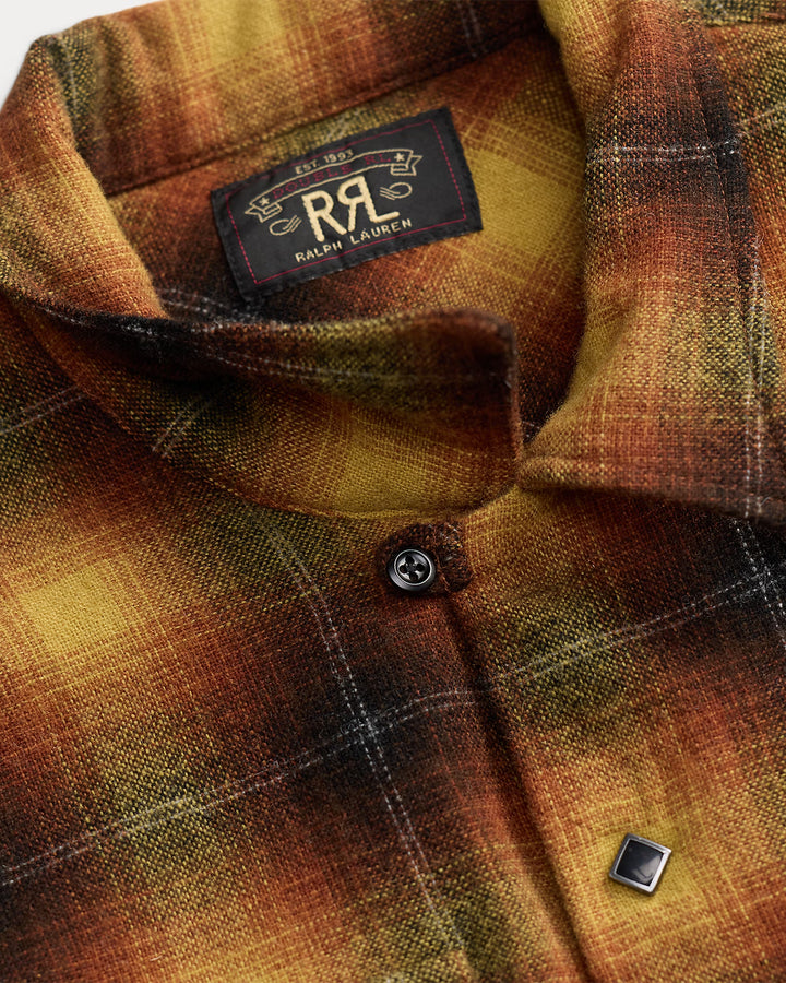 Close-up of a Ralph Lauren plaid button-up shirt in warm autumn tones of brown, orange, and yellow, showing the inner neck label and a silver-toned chest button.