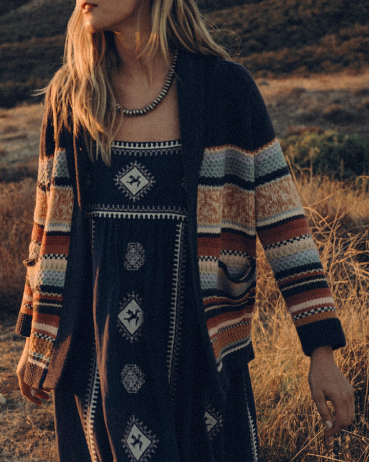 Person wearing a patterned cardigan in a natural setting
