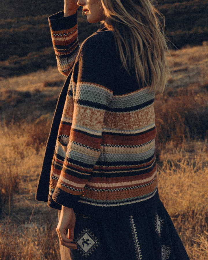 Person wearing a striped sweater in a field