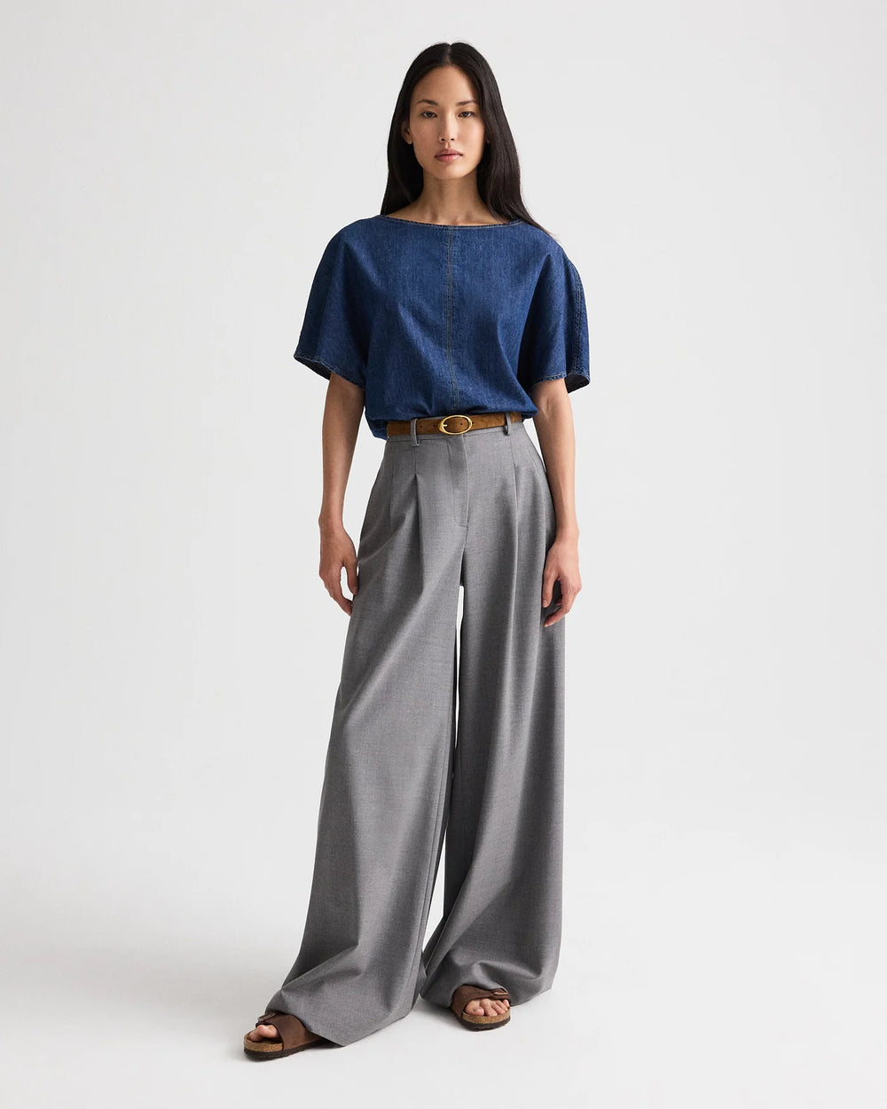 Woman wearing a blue top and gray wide-leg pants on a white background