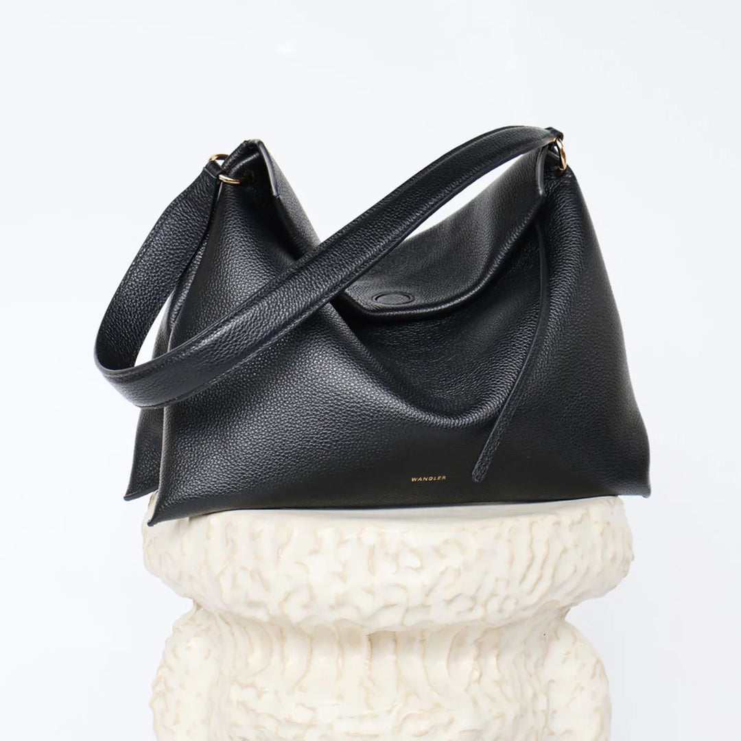 Black leather handbag on a textured white surface