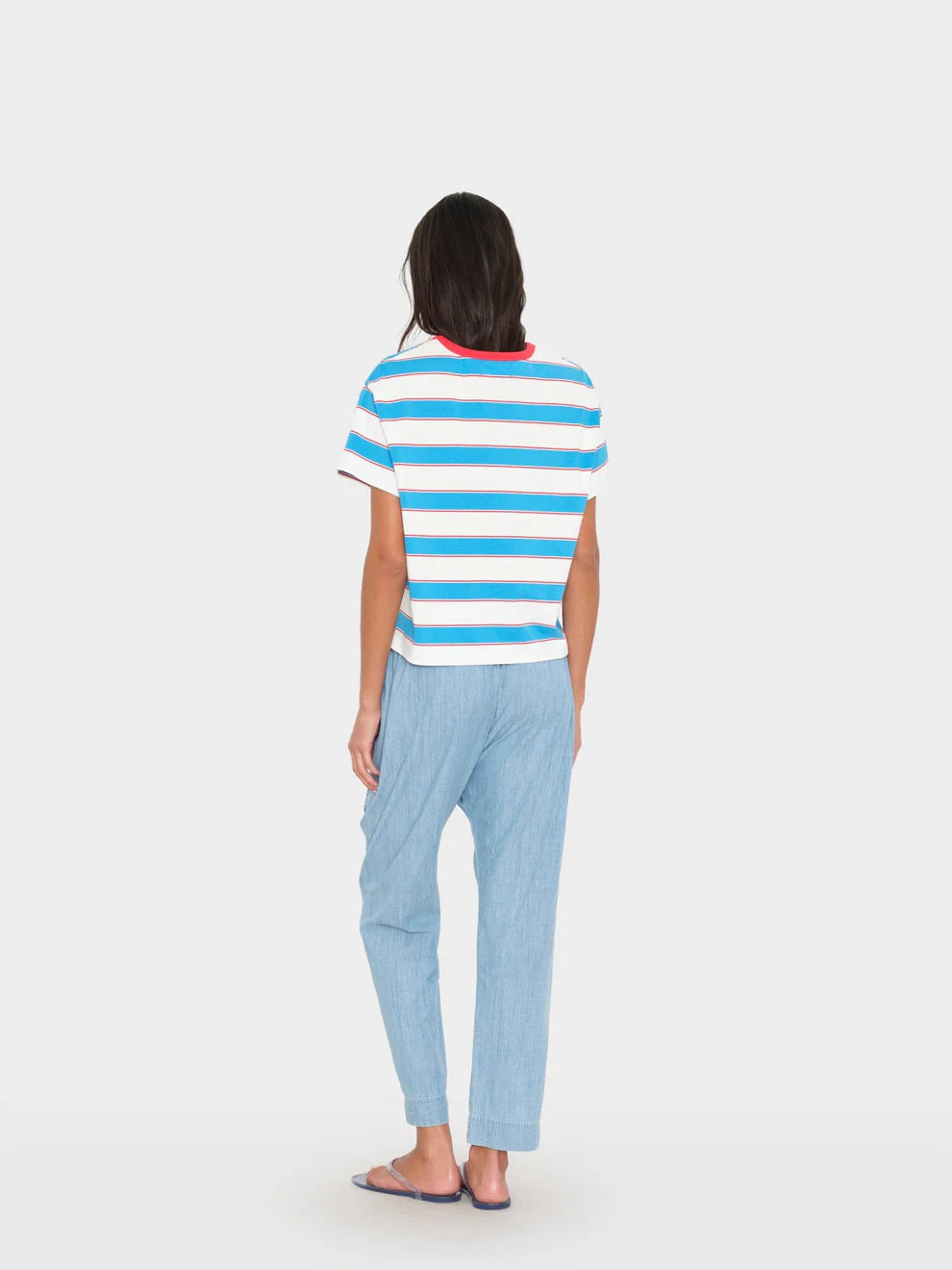 Person wearing a striped shirt and light blue pants on a white background
