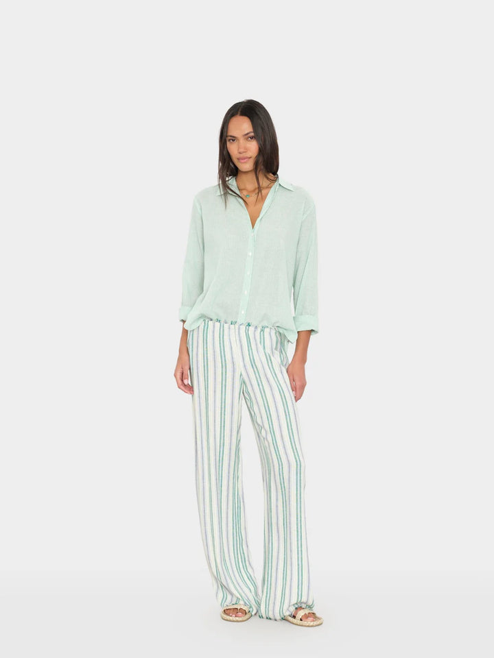 Woman wearing a light green shirt and striped pants on a white background