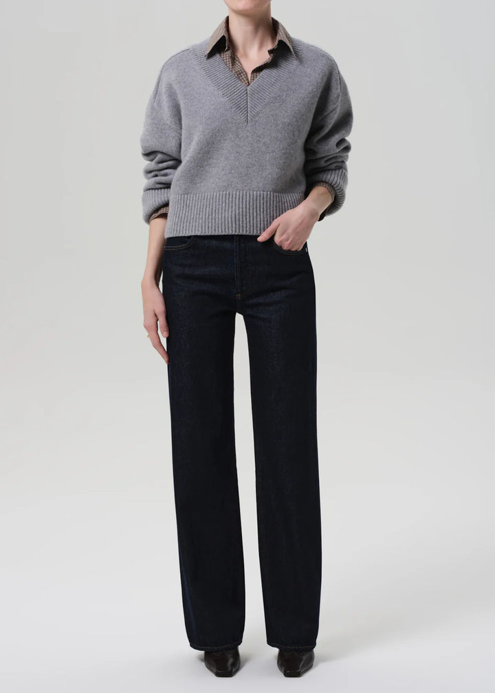 Person wearing a gray sweater and black pants on a white background