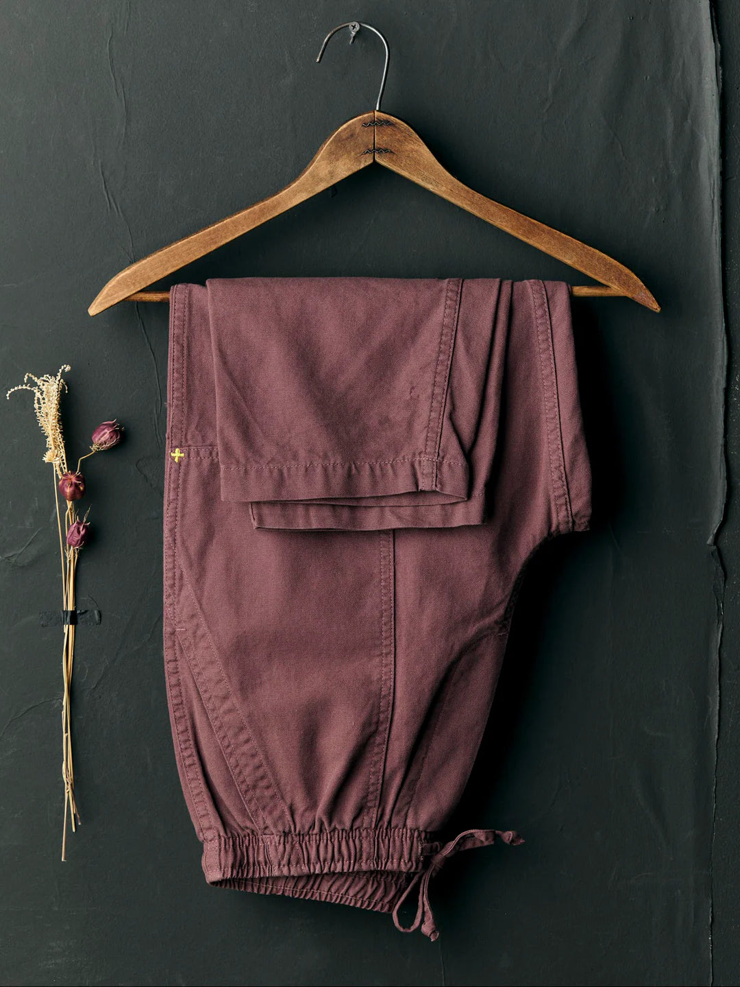 Purple pants on a wooden hanger against a dark background
