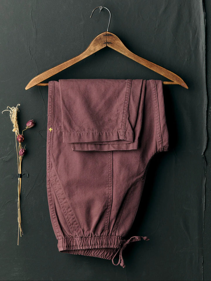 Purple pants on a wooden hanger against a dark background