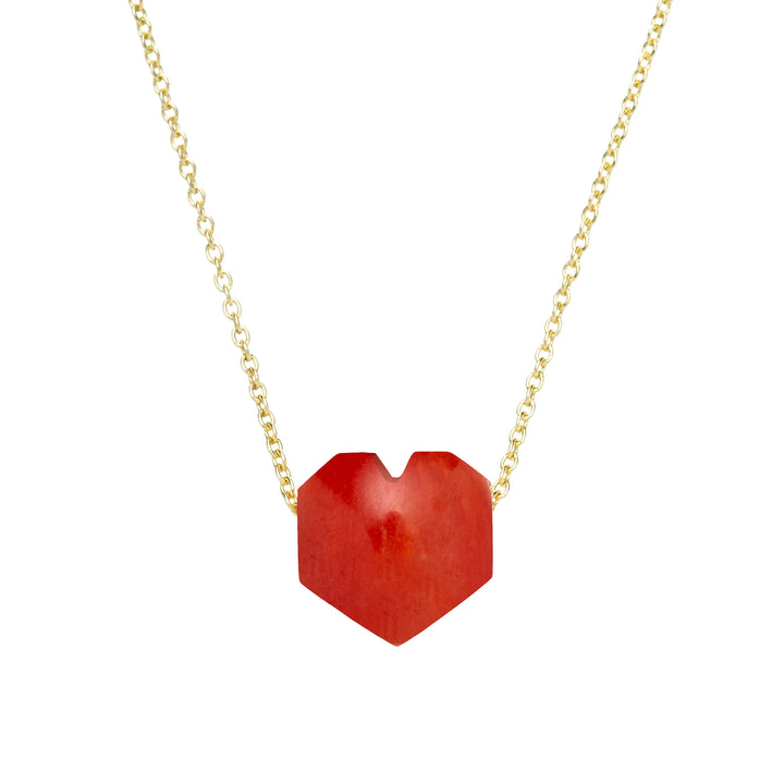 Red heart-shaped pendant on a gold chain against a white background