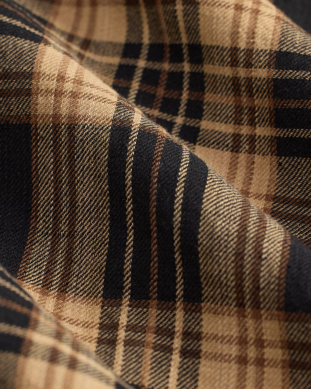 Close-up of plaid fabric with brown, black, and beige colors.
