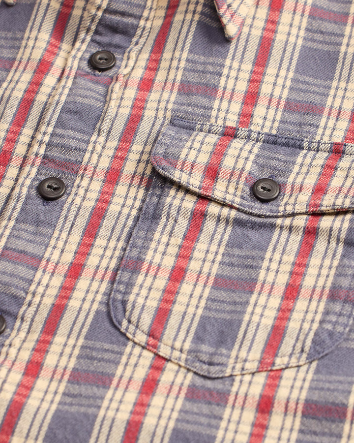 Close-up of a plaid shirt with red, blue, and beige colors.